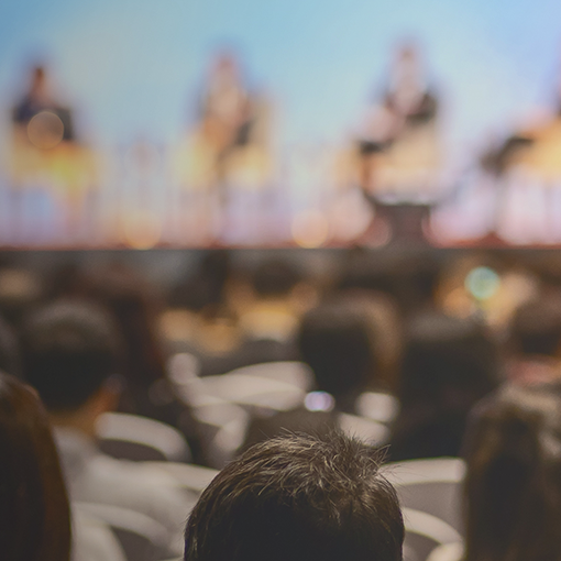 backview of audience listening to speakers at a conference